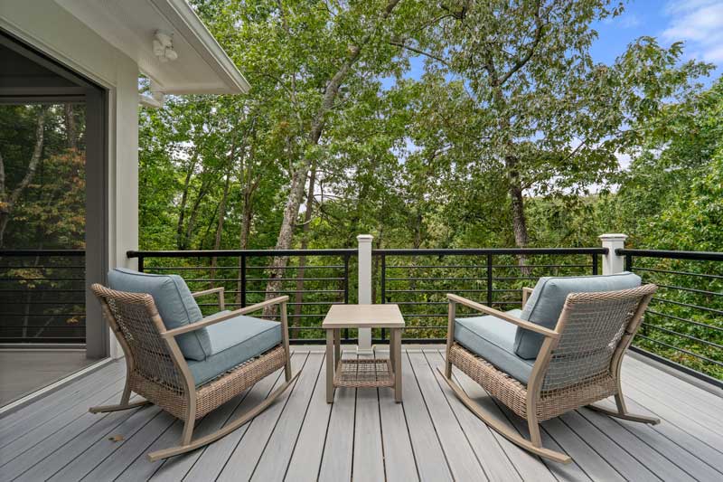 Outdoor deck with two lounge chairs overlooking trees